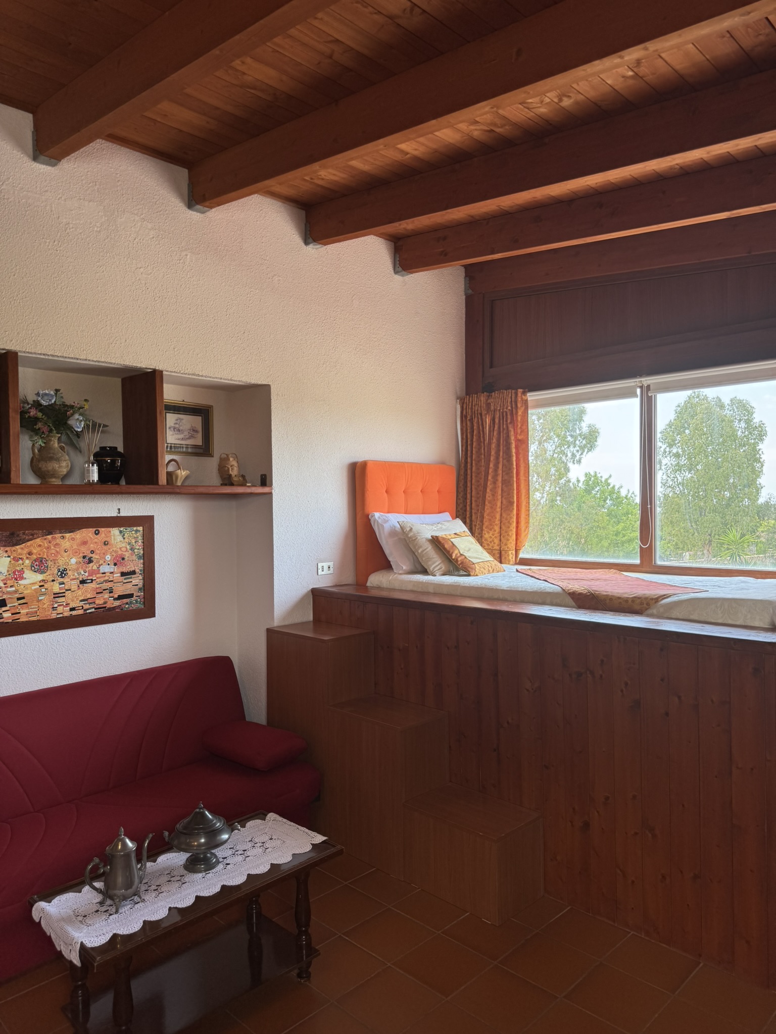Suite — zona living con divano e letto rialzato, travi a vista