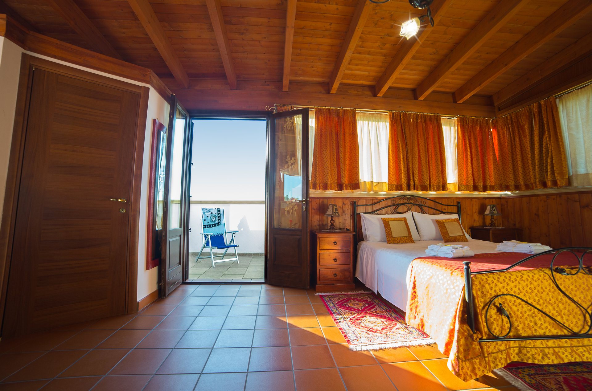 Suite — porta aperta sul terrazzino, travi a vista